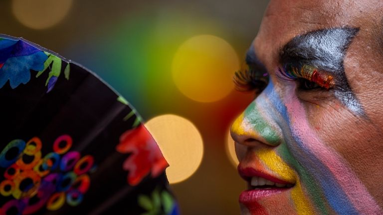 A participant has colors painted on face as LGBTQ+ people...