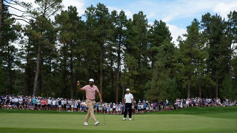 Scottie Scheffler, center left, waves to the gallery on the...