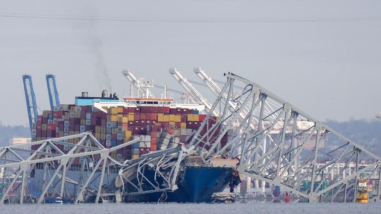 A container ship rests against wreckage of the Francis Scott...