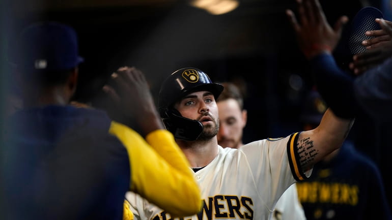 Milwaukee Brewers' Garrett Mitchell is congratulated in the dugout after...