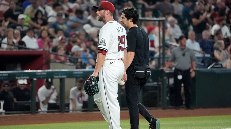 An injured Arizona Diamondbacks starting pitcher Merrill Kelly walks off...