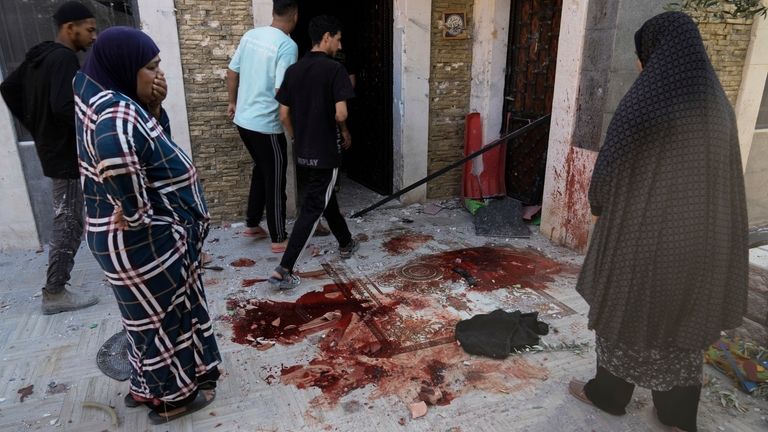 Palestinians look at blood stains at the site of an...