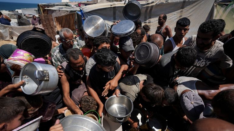 Displaced Palestinians at a food distribution center in Deir al...