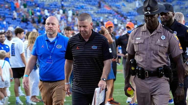 Florida head coach Billy Napier, center, walks off the field...