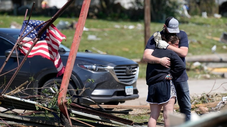 Local residents hug in front of their tornado damaged home,...
