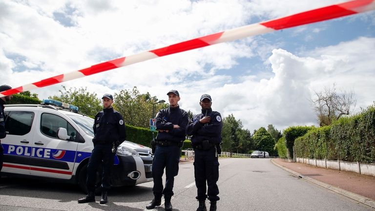 French police officers block the road leading to a crime...