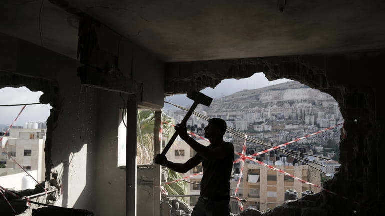 A Palestinian clears rubble after Israeli forces demolished the home...