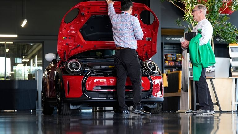 A salesperson shows an unsold 2024 Cooper SE electric hardtop...