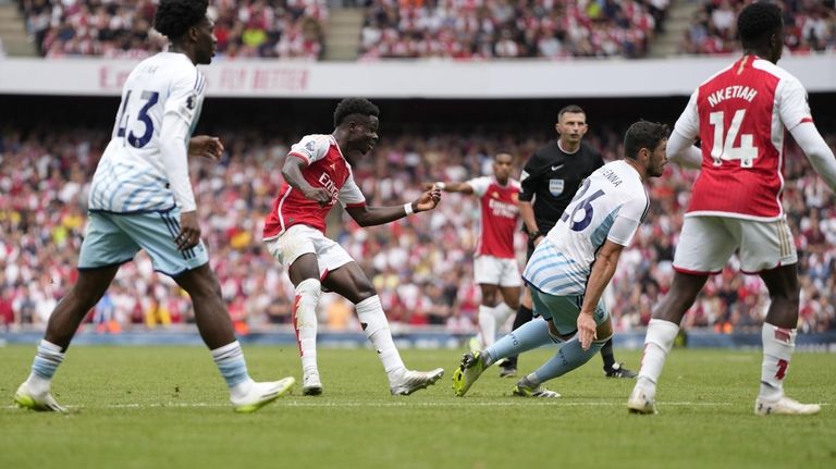 Arsenal's Bukayo Saka, center, scores during the English Premier League...