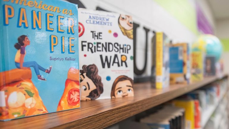 Books sit on shelves in an elementary school library in...