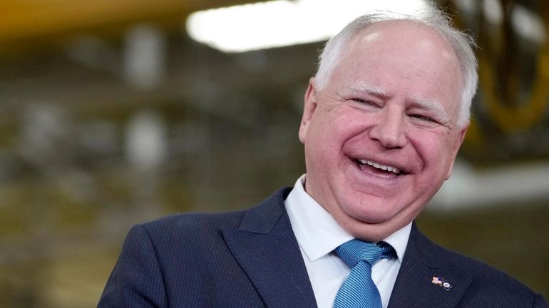 Minnesota Gov. Tim Walz, right, laughs as he stands with...