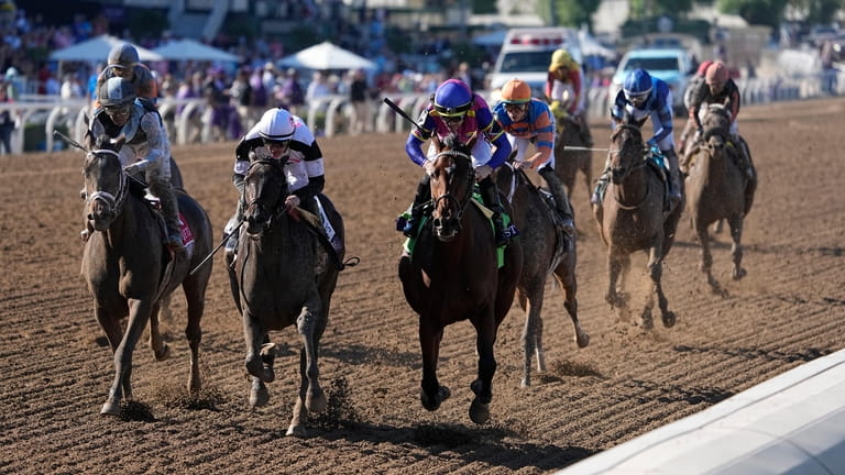 Junior Alvarado rides Just FYI, center, to win the Breeders'...