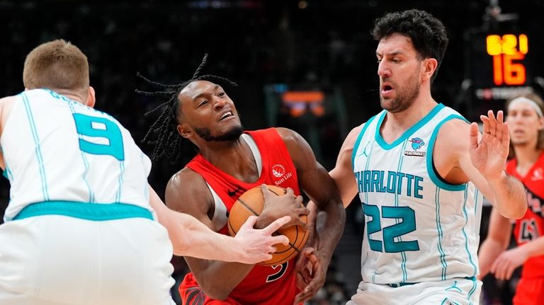 Toronto Raptors guard Immanuel Quickley, center, moves between Charlotte Hornets...