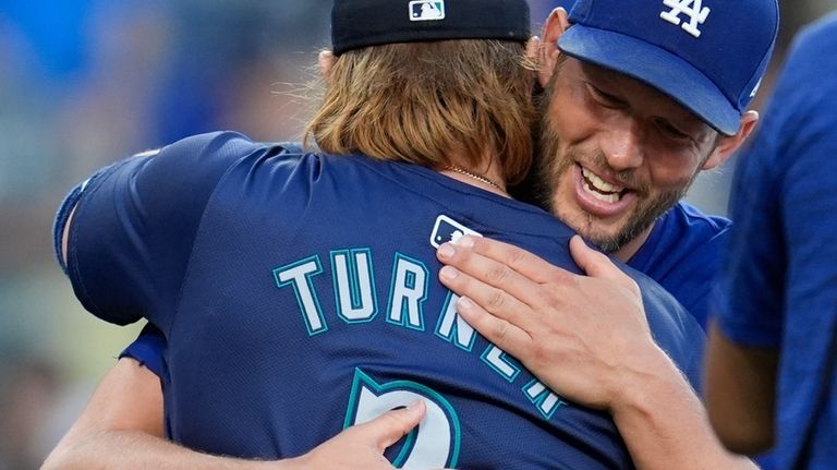 Seattle Mariners' Justin Turner is hugged by former teammate Clayton...