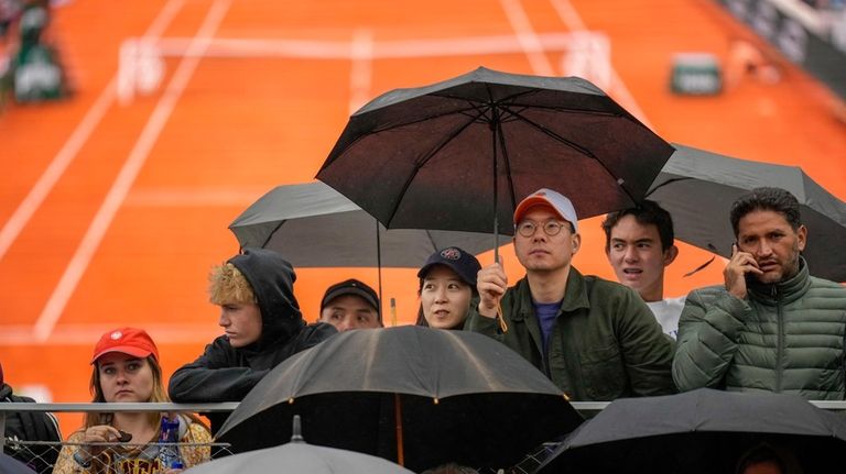 Spectators take cover from the rain during first round matches...