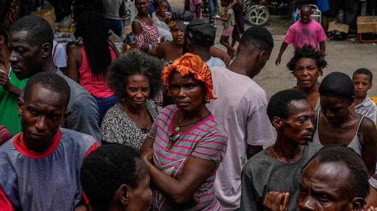 People displaced by gang violence listen to health instructions at...