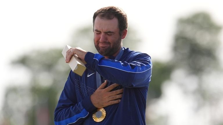 Gold medalist Scottie Scheffler, of the United States, cries as...