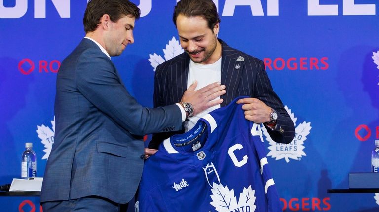 Former Toronto Maple Leafs captain John Tavares, left, hands the...