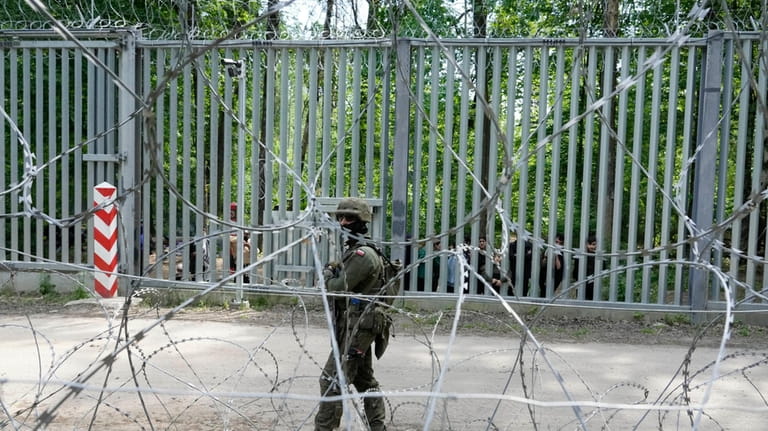 A Polish soldier patrols the metal barrier border with Belarus,...