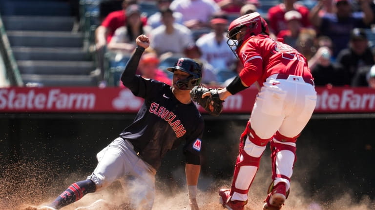 Los Angeles Angels catcher Matt Thaiss, right, tags out Cleveland...