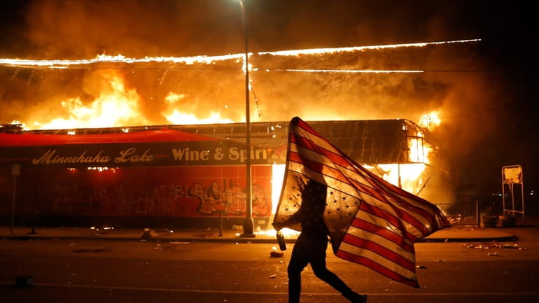 A demonstrator next to a burning building in Minneapolis in...