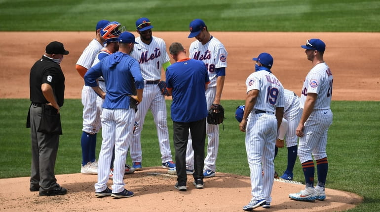 A New York Mets trainer checks on starting pitcher Jacob...