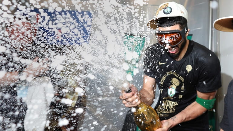 Boston Celtics forward Jayson Tatum sprays champagne while celebrating after...