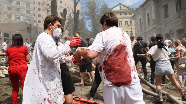 Rescuers, medical staff and volunteers clean up the rubble and...