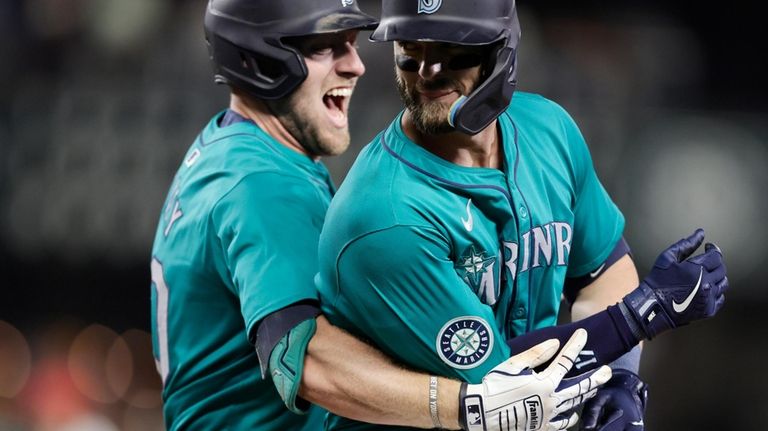 Seattle Mariners' Mitch Haniger, right, is hugged by Luke Raley...