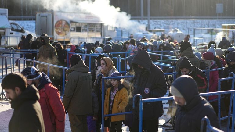 Migrants queue to receive hot food at a logistics center...