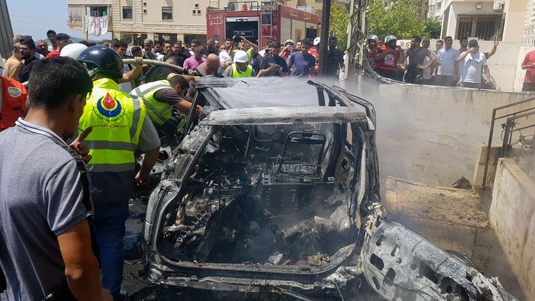 Civil Defense workers inspect the remains of a burned car...