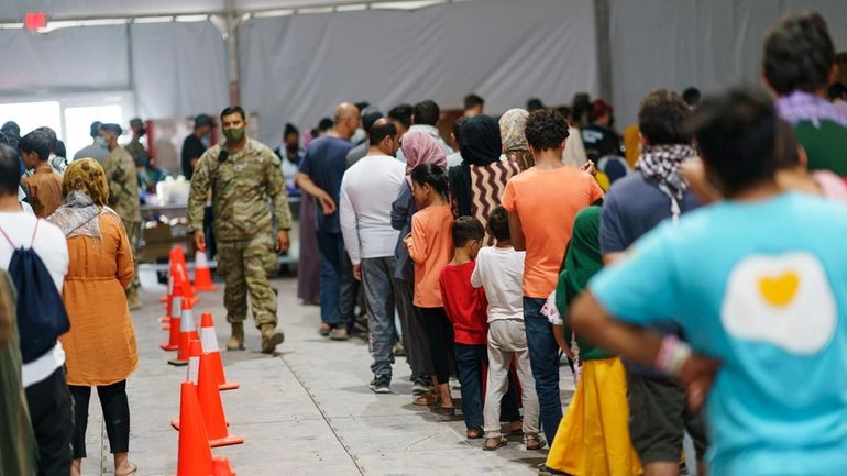 Afghan refugees line up for food in a dining hall...