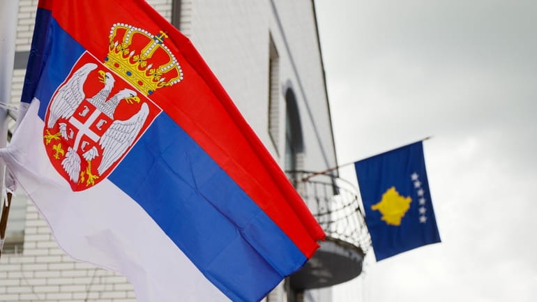 The Serbian flag, left, flies on a lamppost in front...