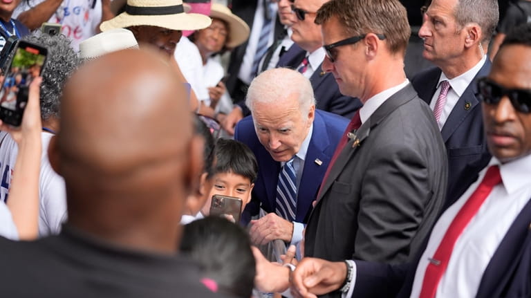 President Joe Biden takes a photo with a child as...