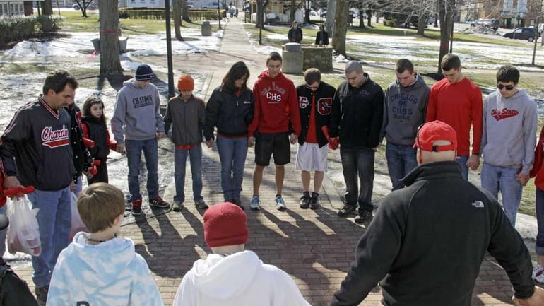 A group of students and parents pray for victims of...