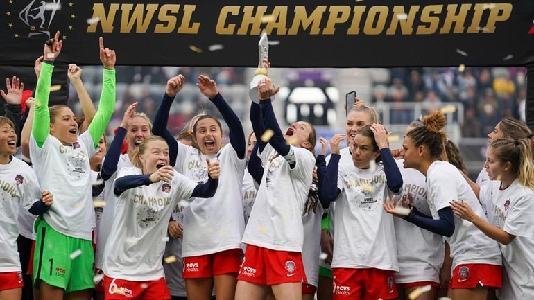 Washington Spirit's Andi Sullivan, center, lifts the trophy as they...