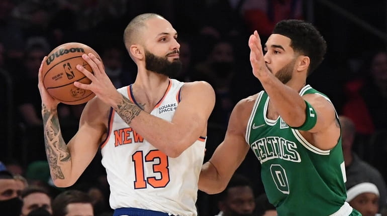 Knicks guard Evan Fournier looks to pass defended by Celtics...