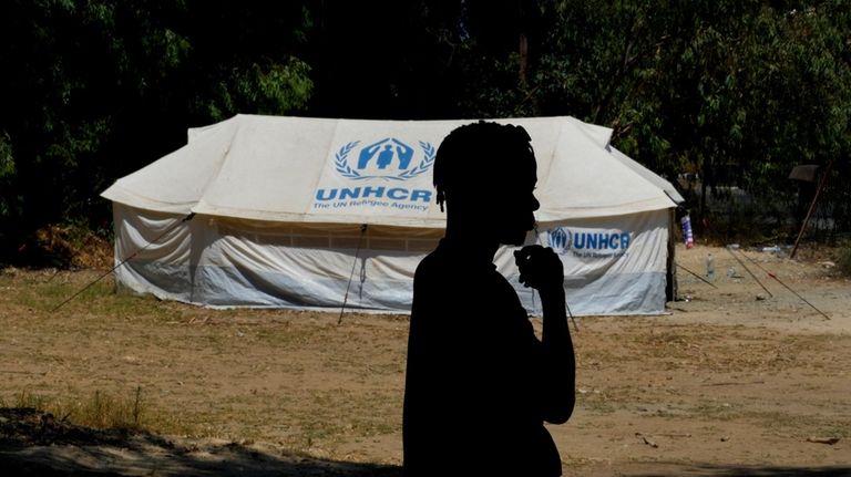 A refugee man stands in front of tent at a...