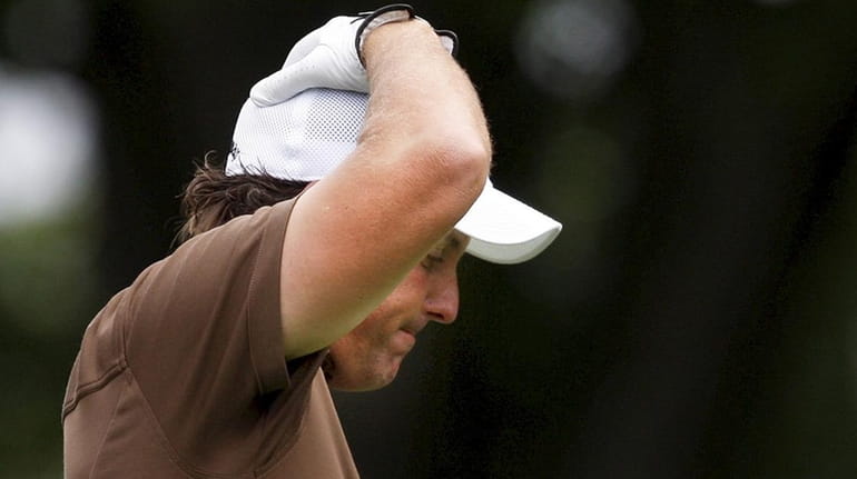 Phil Mickelson reacts to his tee shot on six during...