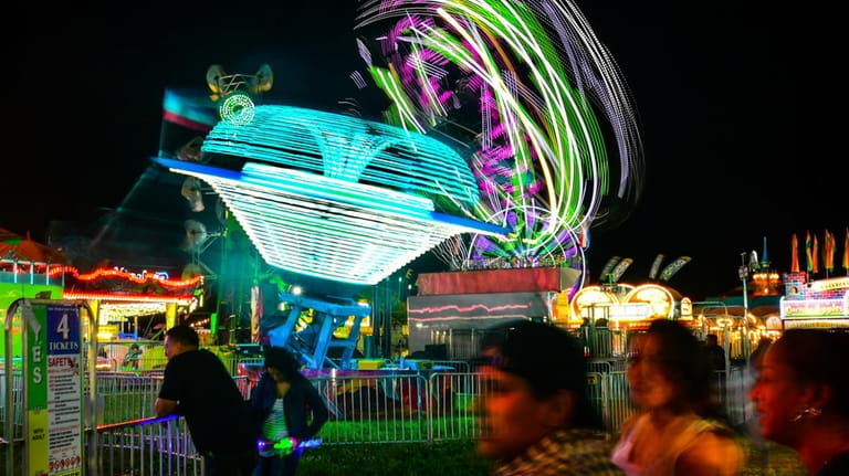 Amusement park rides spin as people attend Long Island Fun...