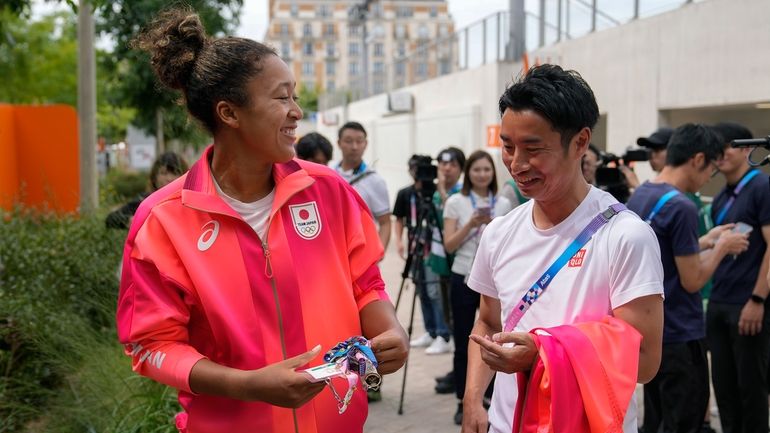 Naomi Osaka, of Japan, left, talks to a journalist after...