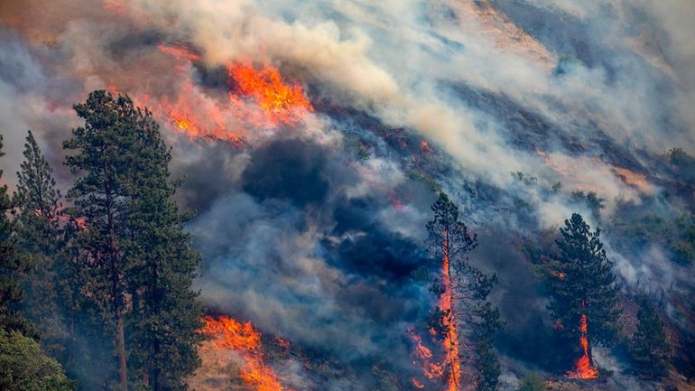 A vehicle drives past the spreading River Fire Thursday, July...