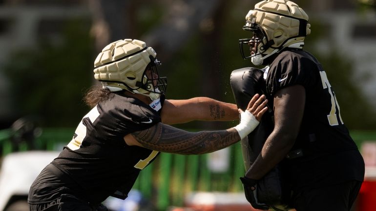 New Orleans Saints offensive tackle Taliese Fuaga, left works on...