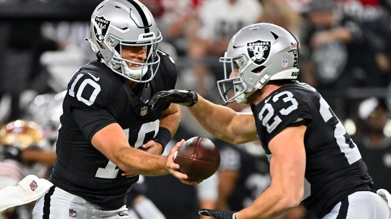 Las Vegas Raiders quarterback Nathan Peterman (10) hands off the...