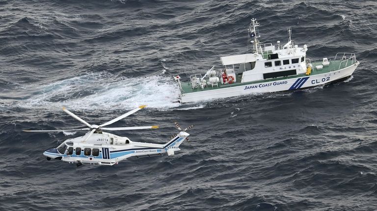 Japanese coast guard helicopter and patrol vessel conduct search and...