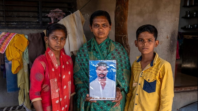 Shobha Londhe, center, holds an image of her husband, farmer...