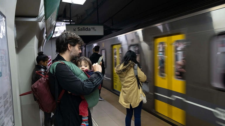 Commuters wait to board a subway car, in Buenos Aires,...
