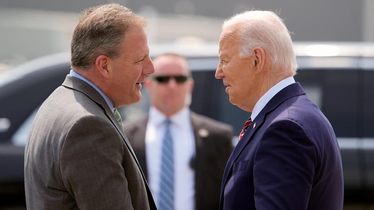 President Joe Biden is greeted by Gov. Chris Sununu, R-N.H.,...