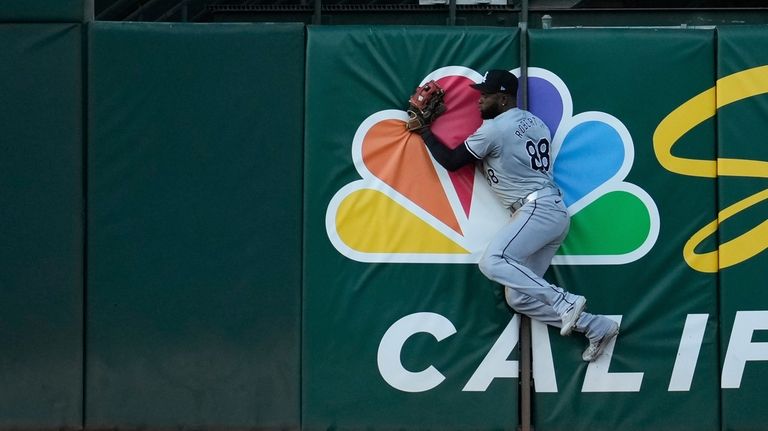 Chicago White Sox center fielder Luis Robert Jr. crashes into...