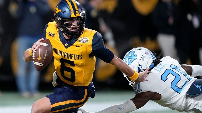 West Virginia quarterback Garrett Greene runs past North Carolina defensive...